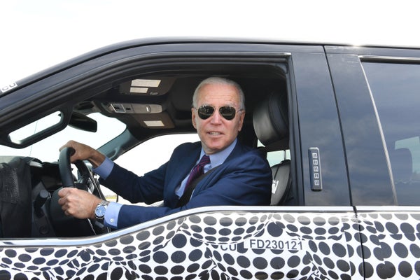 Joe Biden excitedly drives the new electric Ford which is adorned with black polka dots.
