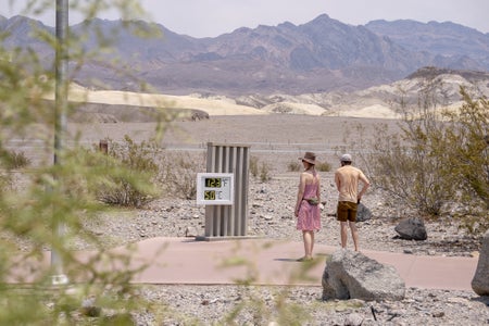 Visitors view the thermometer at the Furnace Creek Visitor Center in Death Valley, California, U.S.