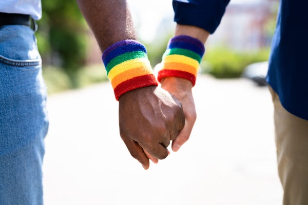 Male couple holding hands with rainbow bands