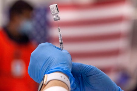 A health worker prepares a syringe and an ampule with a dose of COVID-19 vaccine.