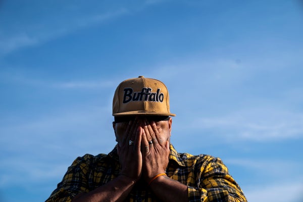 Man in Buffalo ball cap covers face with hands