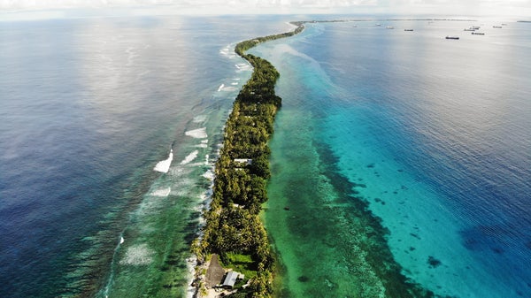 Aerial view of Tuvalu island curling through green and blue water.