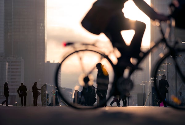 Morning image of businessman on bicycle passing skyline of La Defense business district in Paris, France.