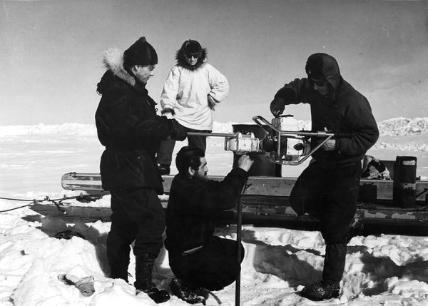 B/w image of scientists drilling hole into ice.