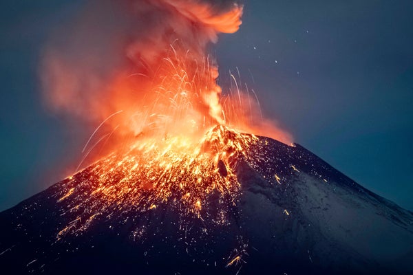 Sparks seems to fly from an erupting volcano against a dark sky