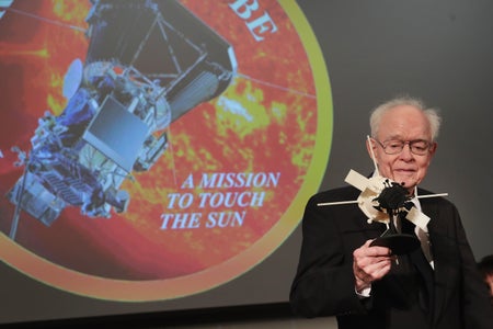 Eugene Parker holding a model of a solar probe.