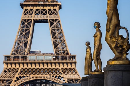A golden statue is seen wearing a blue protective face mask at Trocadero, in front of the Eiffel Tower in Paris.