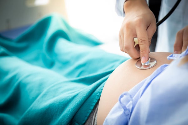 Cropped Hand Of Doctor Examining Belly Of Pregnant Woman In Hospital