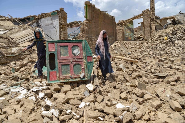 Afghan men look for their belongings amid the ruins of a house damaged by an earthquake in Bermal district, Paktika province, on June 23, 2022.