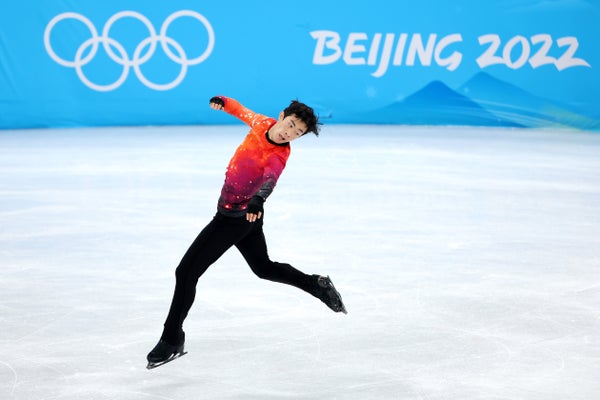 Nathan Chen mid-jump on ice rink.