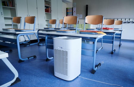 An air purifier sitting underneath a desk.