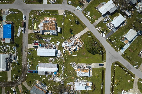 An overhead aerial view showing a neighborhood with widespread damage to homes after a hurricane