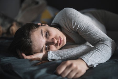 Depressed young woman laying in bed