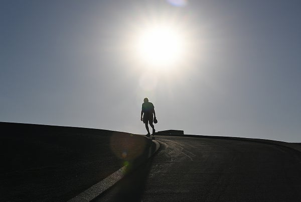 Silhouette of man on hill underneath bright sun