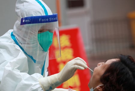 A medical worker collects a throat swab from a patient.