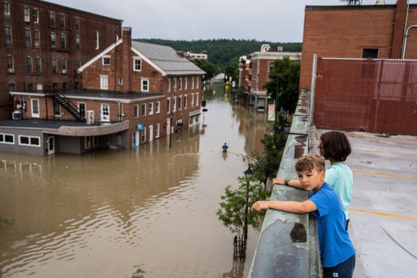 Two children standing above a flooded street in Montpelier, Vermont.