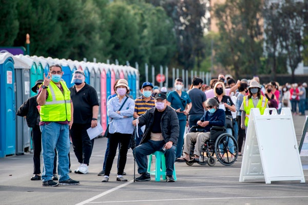 People wait in line in a Disneyland parking lot to receive Covid-19 vaccines.
