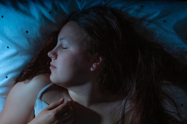 Top view of young woman sleeping cozily on a bed at night