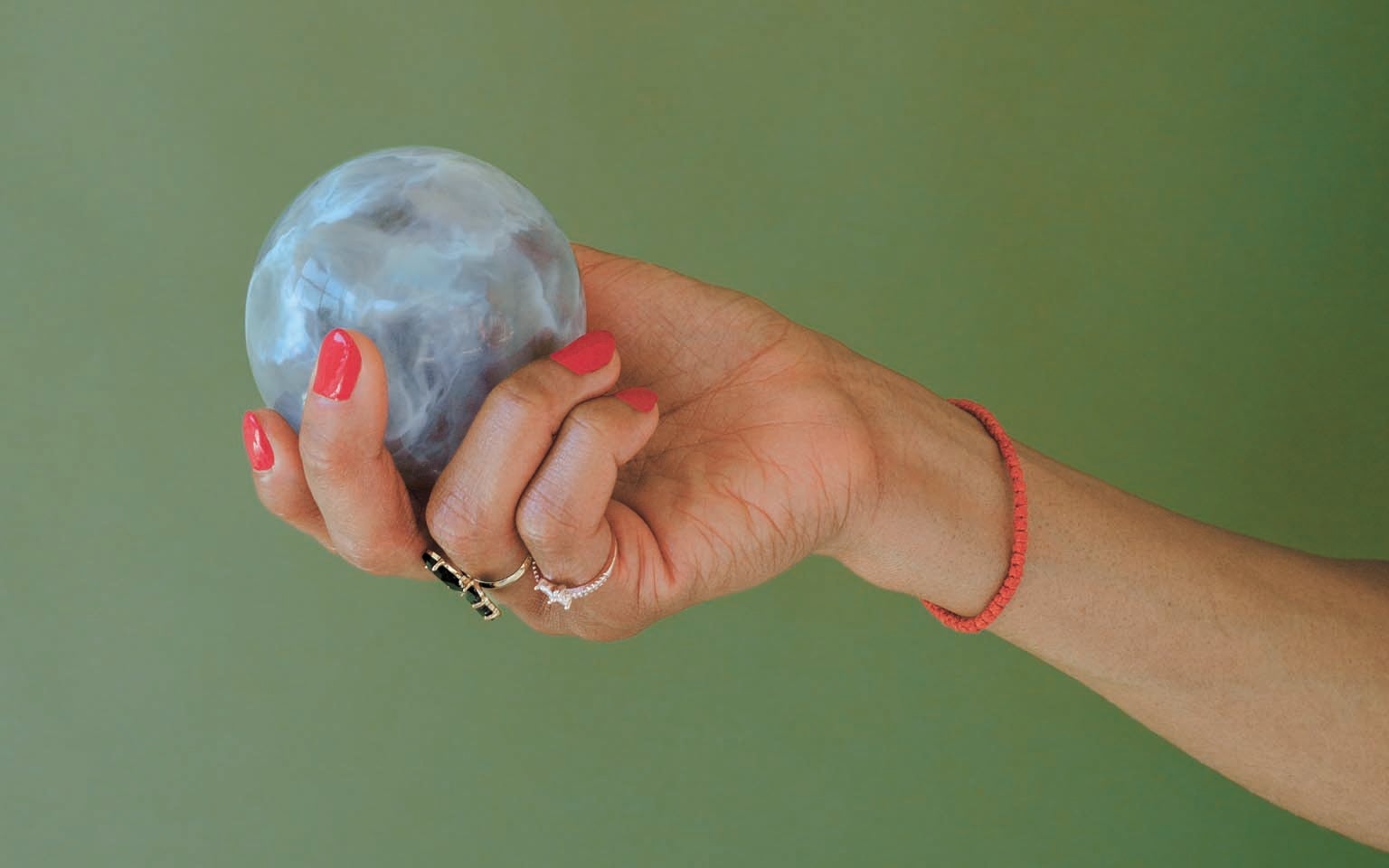 A hand holding a 3-D-printed globe against a green background.