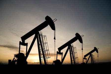 Three pumpjacks on a prairie at sunrise.