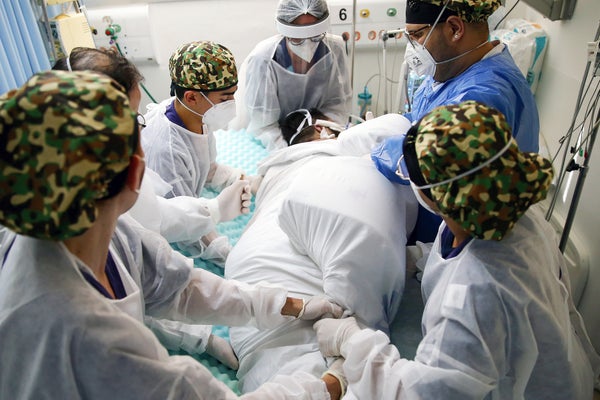 Healthcare workers gather around a patient's bed.