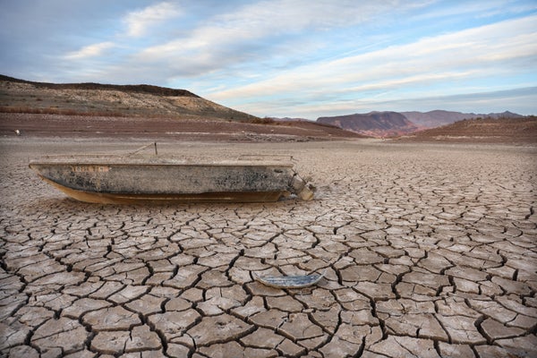 A formerly sunken boat rests on a now-dry section of lakebed.