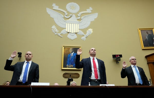 Three men hold their hands up to take an oath before Congress.