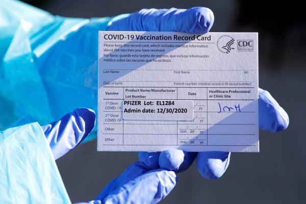 A doctor holds a Covid vaccination card