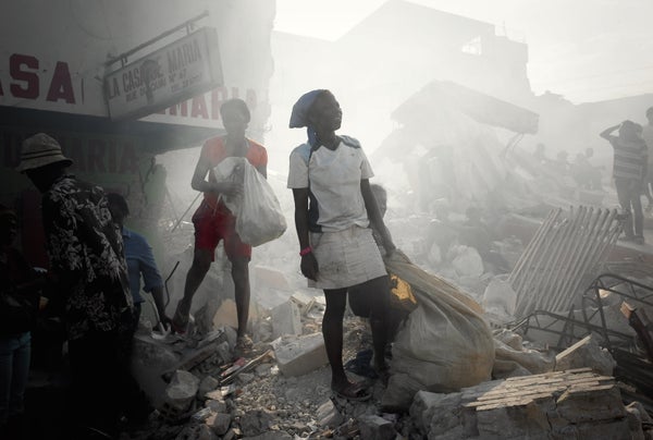 Haitians walk through the smoke of burning rubbish on the street after 2010 earthquake.