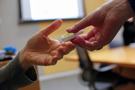 Close up of a person handing a small plastic bottle to another person