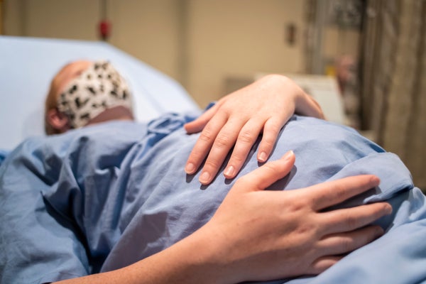 A pregnant woman laying on a hospital bed holding her belly.