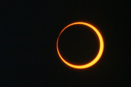 Photograph of a solar eclipse, a glowing orange ring surrounded by black