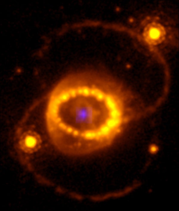 Combination of a Hubble Space Telescope image of SN 1987A and the compact argon source in Fig. 2. The faint blue source in the center is the emission from the compact source detected with the JWST/NIRSpec instrument