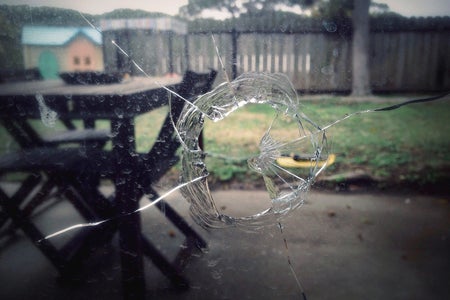 Shattered home window views from inside with patio furniture and yard seen outside
