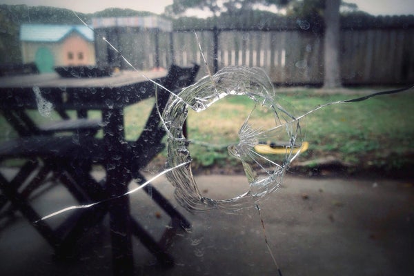 Shattered home window views from inside with patio furniture and yard seen outside