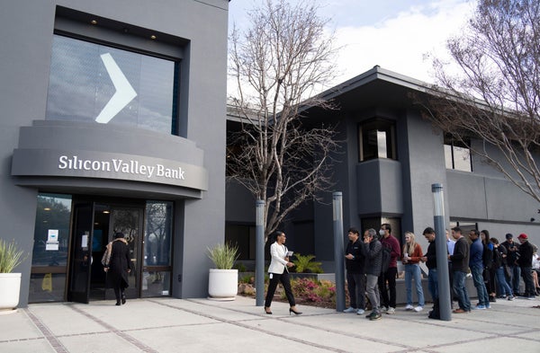 A line of people outside of a bank.