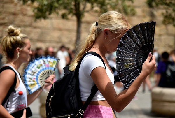 Two women use fans to fight the scorching heat during a heatwave in Seville, Spain, on June 13, 2022.