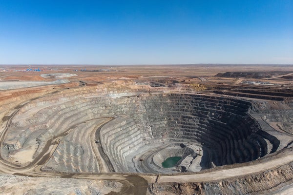 Aerial photograph of an open pit copper-gold mine in desert landscape and blue skies background.