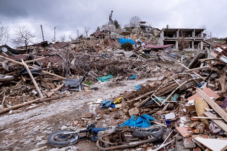 A statute is shown at the top of a pile of earthquake rubble.