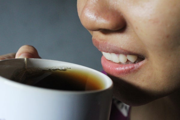 Asian woman smiling, smelling cup of tea