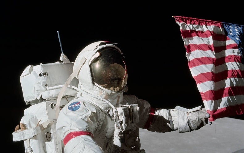 neil armstrong on the moon holding flag