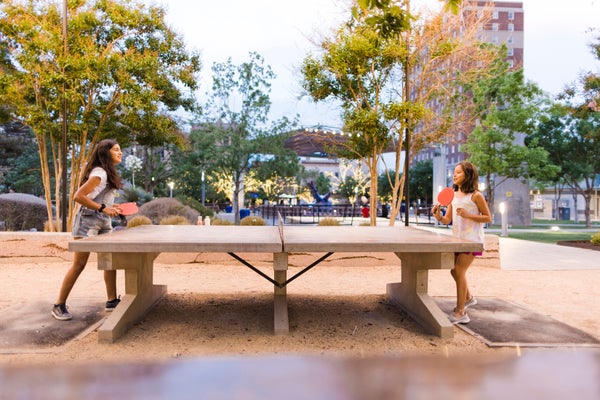 Pre-teen hispanic girls playing table tennis at city park