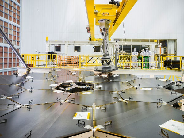 Technicians look over the 6.5-meter primary mirror of the James Webb Space Telescope