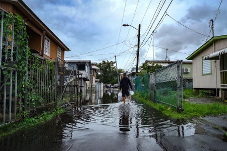 A man walks down a flooded street in the Juana Matos neighborhood of Catano, Puerto Rico.