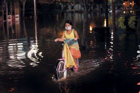 A little girl biking through flooded street.