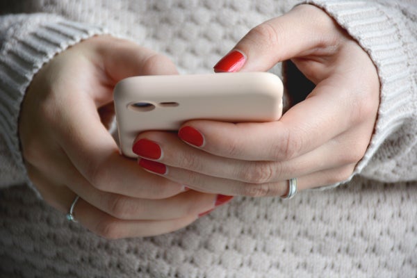 Close up woman with red nails using her mobile phone. Sending a message with smartphone.