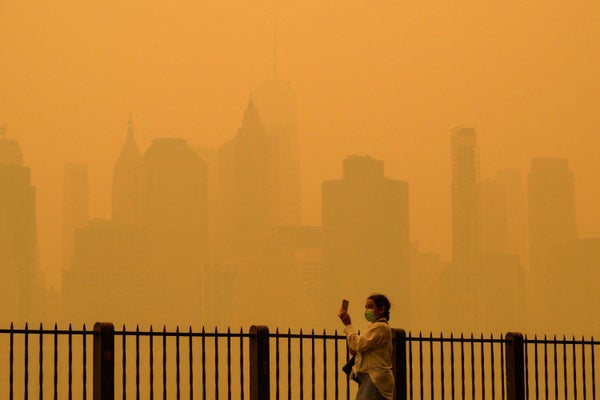 Person walking with face mask during heavy air pollution in front of NYC yellow skyline