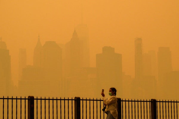 Person walking with face mask during heavy air pollution in front of yellow New York skyline