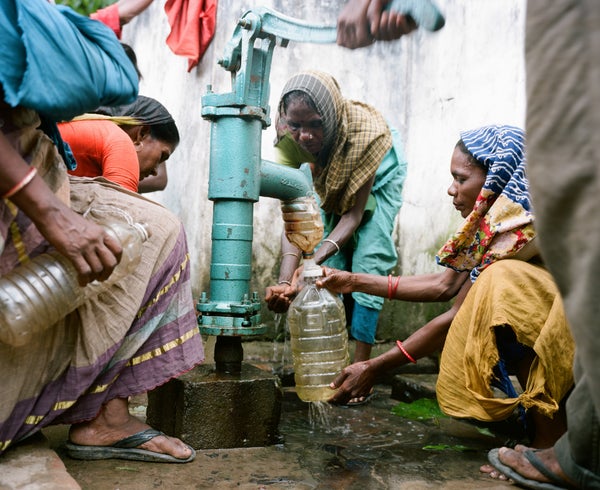 Group of women pumping water from a well.