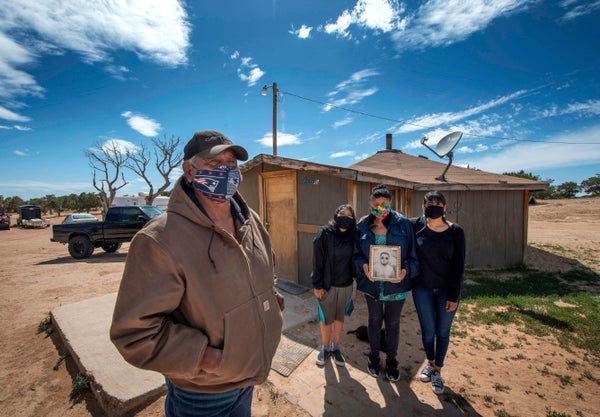 Navajo elder and three family members pose outside residence on a sunny day in Apache County, Arizona.